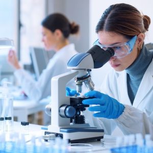 Researchers working in the clinical laboratory Young scientists conducting research investigations in a medical laboratory, a researcher in the foreground is using a microscope